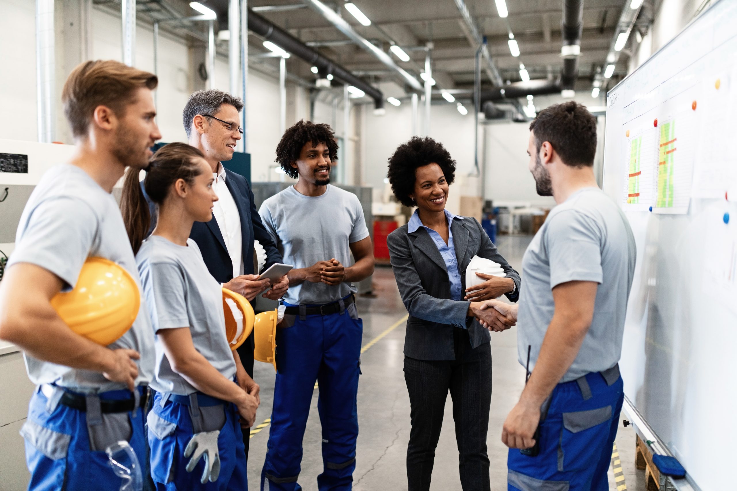 African American businesswoman handshaking with a worker while visiting factory.